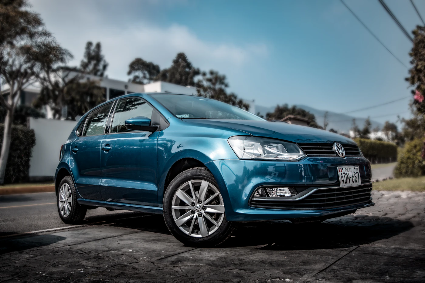 Carro hatch azul estacionado ao sol